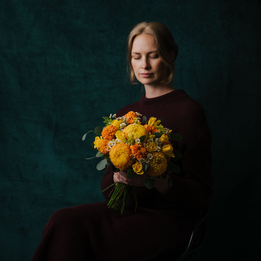 a woman holding a bouquet of yellow flowers